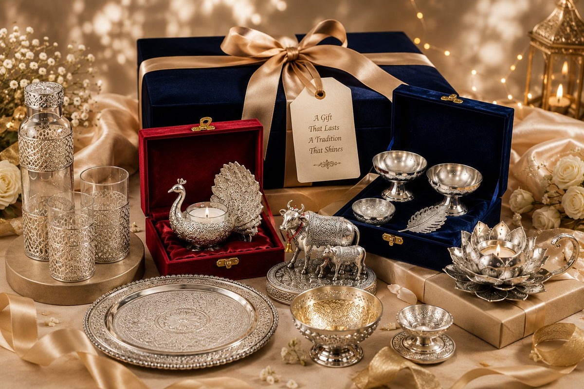 A navy velvet gift box tied with a gold ribbon and hand-written tag, surrounded by German Silver bowls, a peacock tealight holder, a Kamdhenu cow idol and an engraved thali