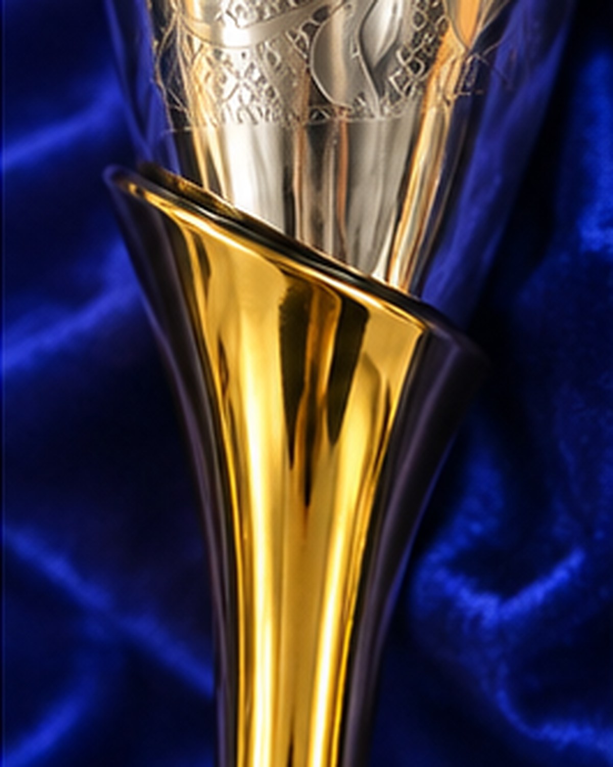 Where the gold polish stem flares into the engraved bowl in a single sweep