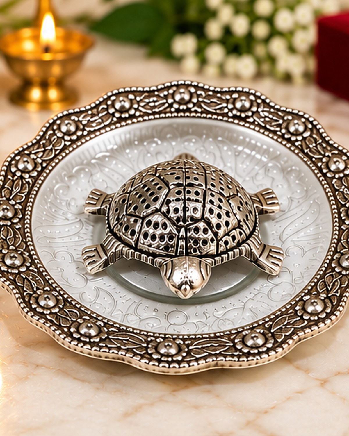 German Silver Kurma tortoise resting on a six inch pooja plate, lit by a diya