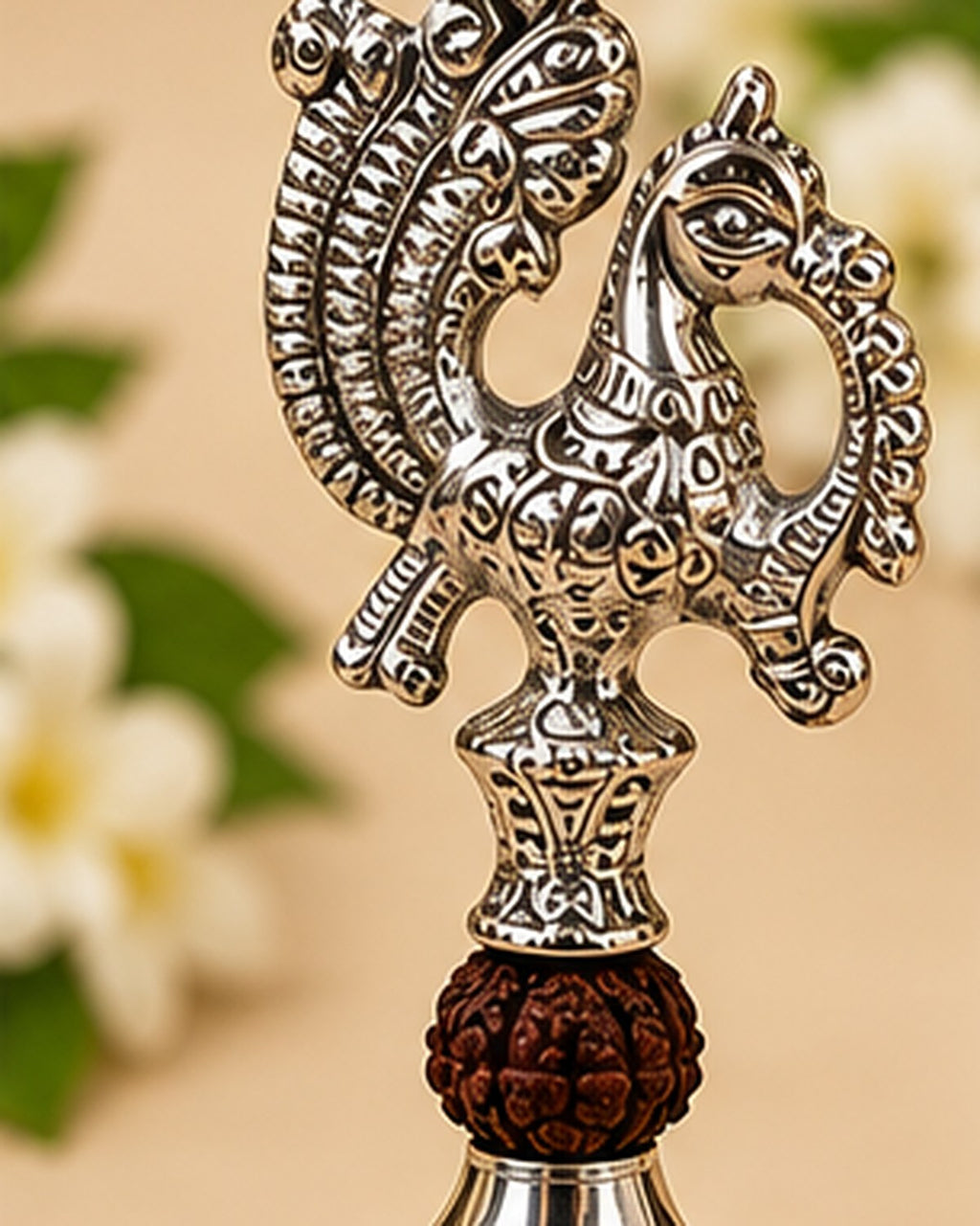 Two peacocks facing each other across the bell handle, above the rudraksha-form bead