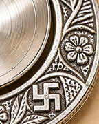 Chased floral border and swastika motif on the rim of the Om diya
