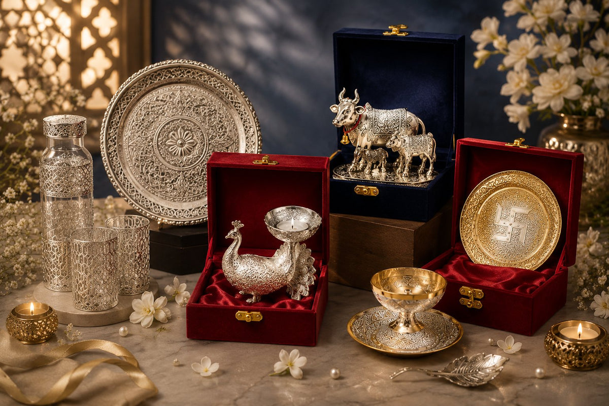 German Silver gift sets in open velvet boxes — an engraved thali, peacock tealight holder, Kamdhenu cow idol and gold-polish bowls, styled with jasmine flowers